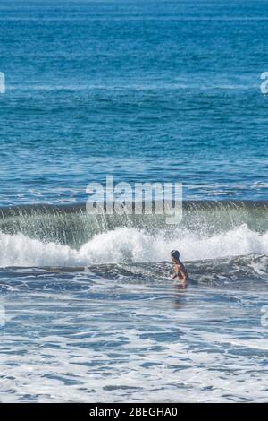Woman in swimsuit enjoying the ocean at Monterrico Beach, Guatemala Stock Photo