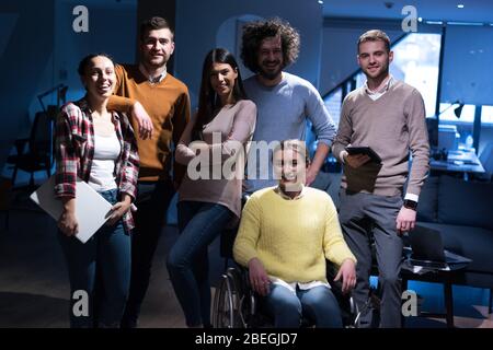 Handicapped young woman with colleagues working in office. Performing in co-working space. Office people working together. Looking into camera Stock Photo