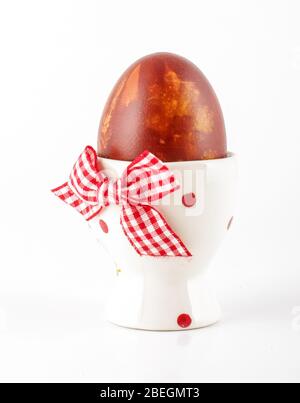 Traditionally brown painted Easter egg in the egg cup isolated on the white background Stock Photo