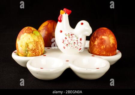 Egg stand made from white porcelain with three Easter eggs isolated on the black background Stock Photo