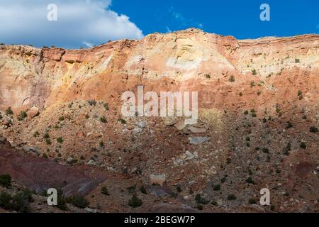 A colorful desert cliff face illuminated a break in the clouds in the American Southwest in northern New Mexico Stock Photo