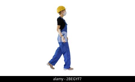 Young woman in hard hat and medical mask walking on white backgr Stock Photo