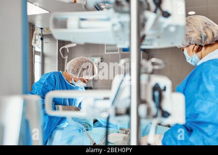 A team of doctors performs an operation. A group of surgeons at work in the operating room, saving the life of the patient from pneumonia. The fight Stock Photo