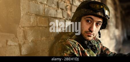 Portrait of confident soldier holding helmet while saluting against ...