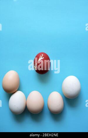 White Easter eggs on blue minimalist background with one red egg . Stock Photo