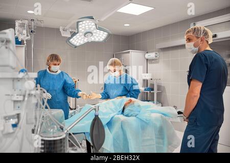 A team of doctors performs an operation. A group of surgeons at work in the operating room, saving the life of the patient from pneumonia. The fight Stock Photo