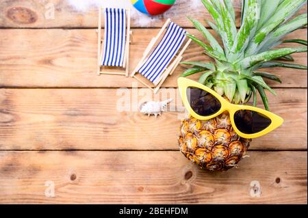 Pineapple with sunglasses on wood background. Creative minimal summer holiday concept with miniature toy. Stock Photo