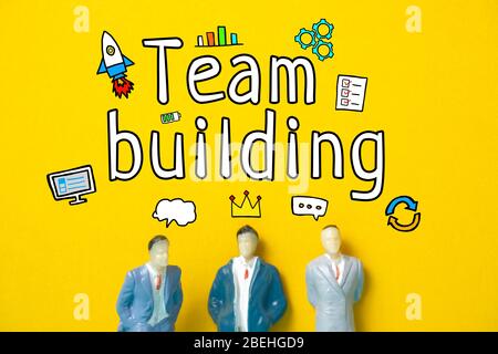 Team building concept - abstract figures of employees on a yellow background with text and icons. Close up. Stock Photo
