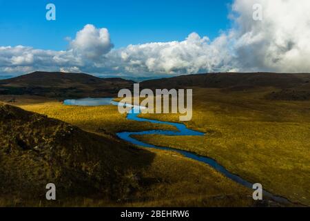 amazing landscape in the countryside with a stream flowing by and a vista view of the clouds and the mountains Stock Photo