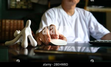 Man working on his computer. Focus on his fingers on the mouse. Work from home concept. Stock Photo