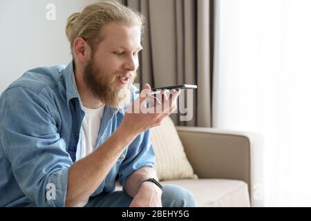 Young man using virtual digital voice assistant on mobile phone app. Stock Photo