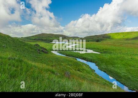 amazing landscape in the countryside with a stream flowing by and a vista view of the clouds and the mountains Stock Photo