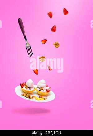 cake on a plate with levitating fork strawberry nuts Stock Photo