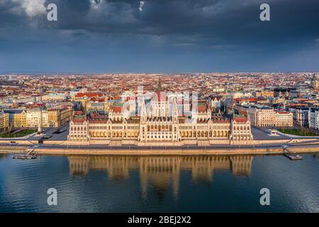 Budapest, Hungary - Aerial view of the beautiful Hungarian Parliament building with reflection and warm golden sunlight at sunset. The streets are tot Stock Photo