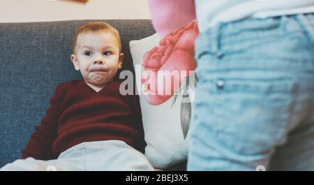 Caucasian mother explaining something to her little son while sitting on sofa and thinking Stock Photo