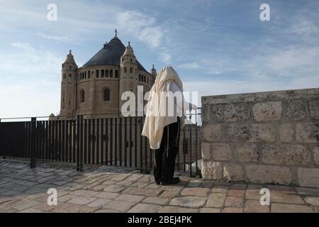 A religious Jew wrapped with Talit customary Jewish prayer shawl praying on top of the Cenacle also known as 'Hall of the Last Supper' a second-story room that commemorates the 'upper room' in which Christian believe Jesus shared the Last Supper with the disciples located directly above the Tomb of David next to the Church of the Benedictine Abbey of the Dormitionon on Mount Zion in Jerusalem Israel Stock Photo