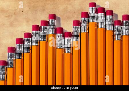 A business bar chart composed of the eraser side of yellow #2 pencils on a dirty linen fiber paper background with room for copy above the chart on th Stock Photo