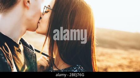 Lovely caucasian couple kissing each other in the field during a sunny day Stock Photo