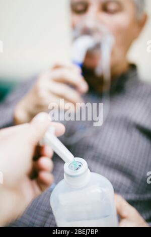 Preparation of compressor nebulizer for use on senior man with respiratory mask, nebulizer in the room Stock Photo