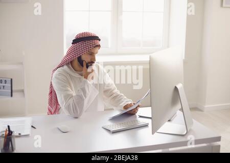 Arab businessman worker with a beard works in computer on the workplace in the office. Busy serious arabian man on a working. Stock Photo