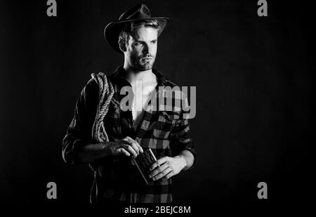 ride a fast horse. cowboy with lasso rope. Western. man checkered shirt on ranch. western cowboy portrait. Vintage style man. Wild West retro cowboy. wild west rodeo. man in hat black background. Stock Photo