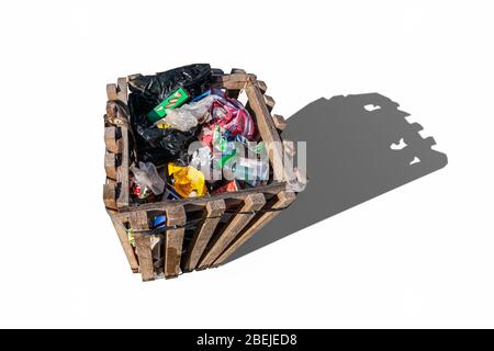 Wooden planks trash can, trash bin isolated on white background. Full Trash Can. Garbage bin with tin cans, bottles, paper cups, biscuit packs. Stock Photo