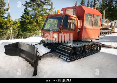 Snow-grooming machine. Snow cat machine making the ski run smooth. Snowcat ready to grooming for skiing and snowboarding on the mountain. Stock Photo