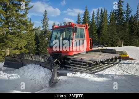 Snow-grooming machine. Snow cat machine making the ski run smooth. Snowcat ready to grooming for skiing and snowboarding on the mountain. Stock Photo