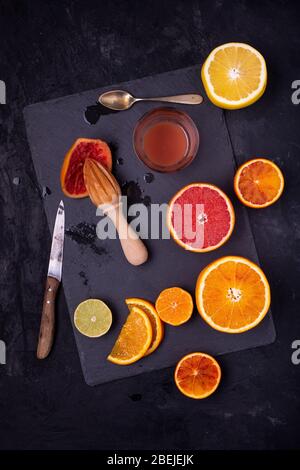 on the slate slab, with a top view, sliced citrus fruits, and freshly squeezed red grapefruit juice Stock Photo