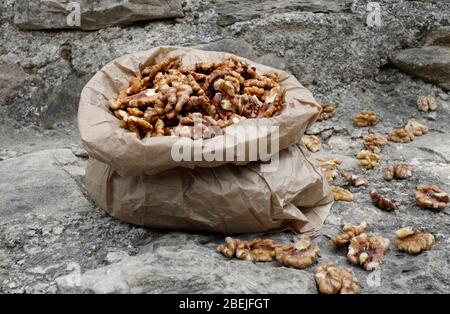 Walnut kernels in paper bag on stone background Stock Photo