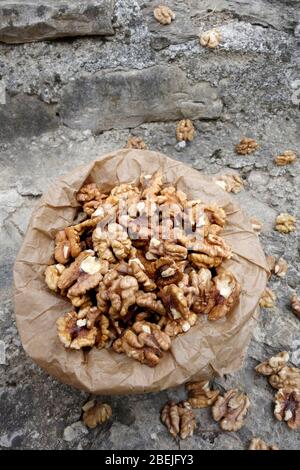 Walnut kernels in paper bag on stone background Stock Photo
