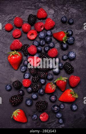 on the rustic and dark background, with a view from above, a mix of fresh berries Stock Photo