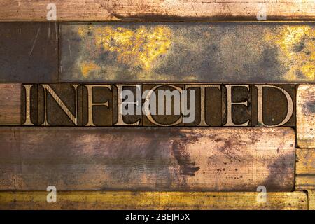 Photo of real authentic typeset letters forming Infected text on vintage textured grunge copper background Stock Photo