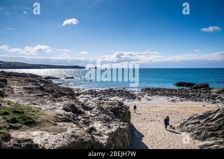 People walking across the sand at the secluded Little Fistral in Newquay in Cornwall. Stock Photo