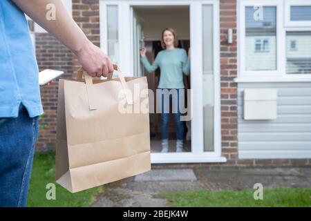 Home Delivery Of Takeaway Food Outside House Observing Safe Social Distancing During Coronavirus Covid-19 Pandemic Stock Photo