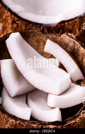 In the foreground, some pieces of fresh coconut in the coconut shell. Stock Photo