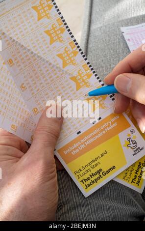 Close up of person man holding filling in EuroMillions Lotto lottery slip form England UK United Kingdom GB Great Britain Stock Photo