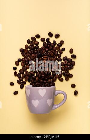 top view, from coffee cup with heart, coffee beans pour isolated on a yellow background, love and passion for coffee. Stock Photo