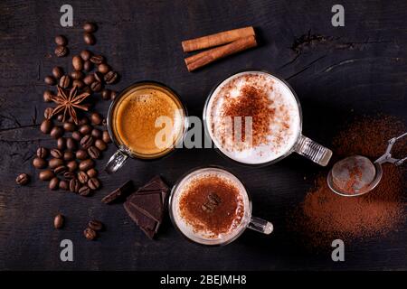 top view, close-up, on the dark wooden background, some types of espresso-based drinks, latte macchiato and cappuccino with a sprinkling of cocoa powd Stock Photo