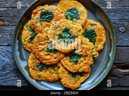 Useful spicy Indian chickpea pancakes with vegetables and parsley in a plate Top view Stock Photo