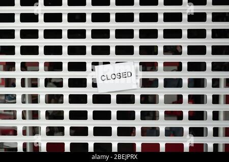 The sign 'closed' on roller blinds of a shop. Concept of retailer stores and shops shut down due to quarantine Stock Photo