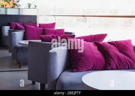 Empty cushions and sofas at a generic cafe. Clean table and chairs against the bright light, generic interior, concept of lockdown due to quarantine Stock Photo