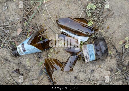 Odessa, Ukraine - April 9, 2020: Broken beer bottle in the sand. A bottle of light beer Robert Doms after the open air party. View from above. Selecti Stock Photo