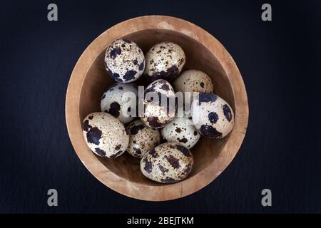 Tiny quails eggs in a bowl taken from above against a black slate background Stock Photo