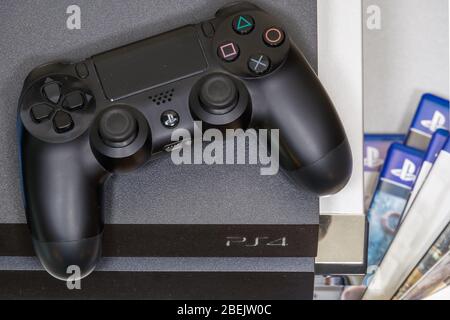 PlayStation 4 DualShock 4 wireless controller top view. Gamepad resting above Sony gaming console with logo. Stock Photo