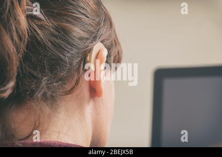 Deaf woman wearing hearing aid and using tablet Stock Photo