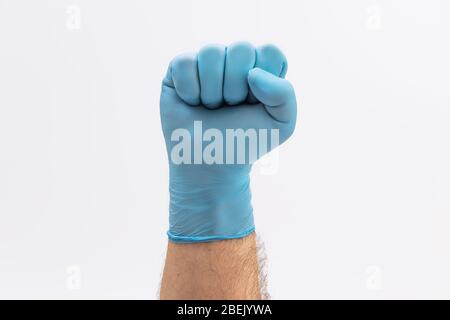 Fist Hand in medical blue latex protective glove as a sign of resistance to pandemic - on white background stop disease sign Stock Photo