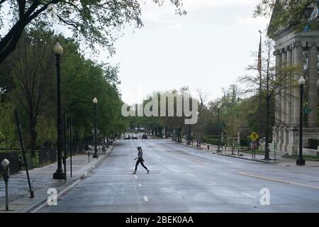 Washington, DC, USA. 13th Apr, 2020. A woman crosses an empty street in Washington, DC, the United States, April 13, 2020. Credit: Liu Jie/Xinhua/Alamy Live News Stock Photo