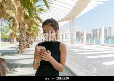 Beautiful woman at Port of Malaga Spain using mobile phone Stock Photo