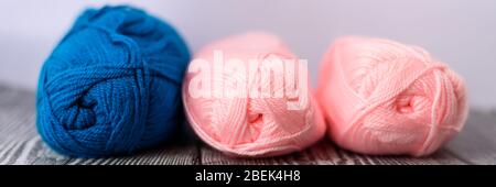 Three colred wool balls laying on the grey wooden background. Banner size. Stock Photo